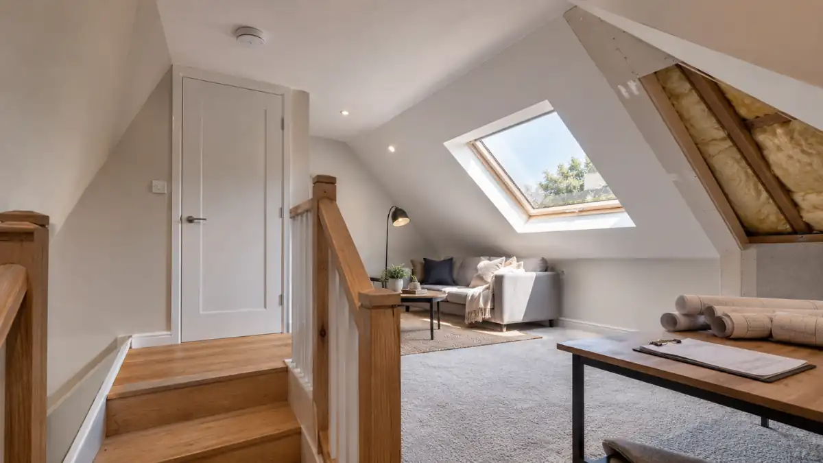 Modern loft conversion interior with skylight window, staircase, and seating area designed to meet building regulations on loft conversions for safe and compliant attic renovations.